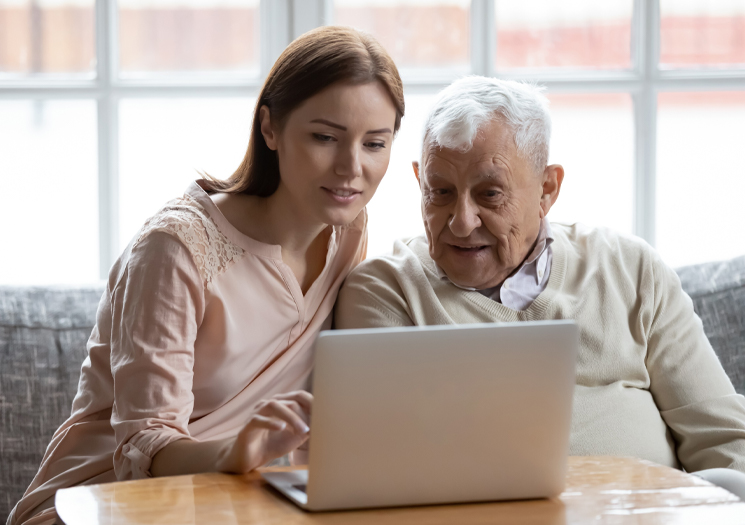woman helping elderly man on computer
